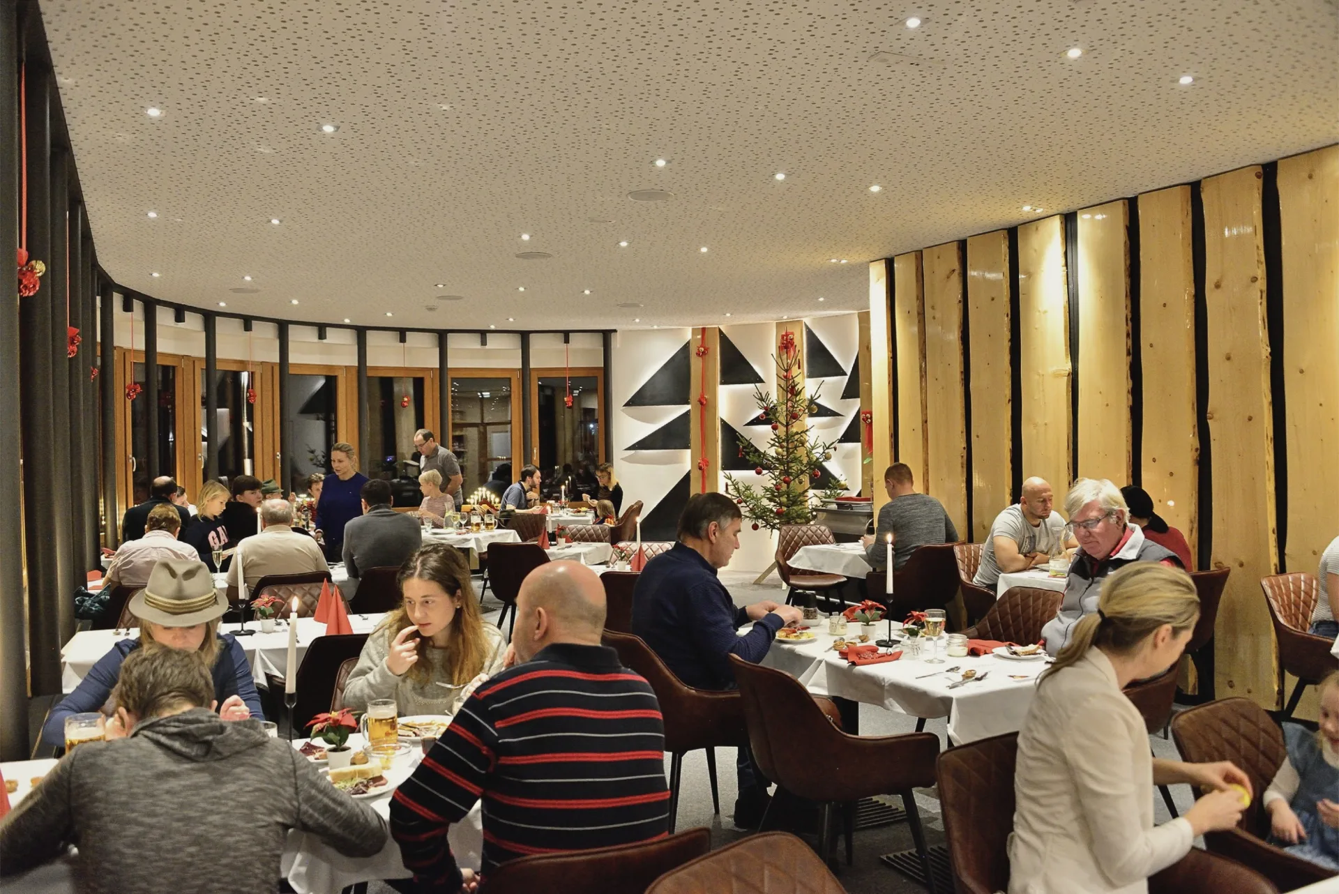 Hosté při společné večeři ve stylové restauraci Montanie Resort v Jizerských horách, s vánoční výzdobou a útulnou atmosférou.