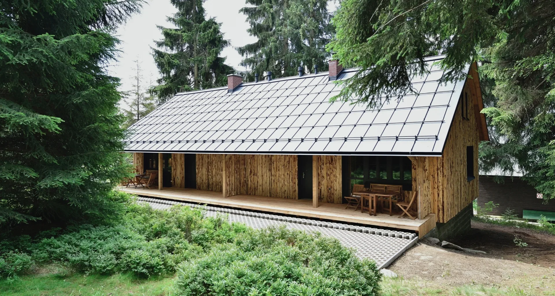 Dřevěný srub resortu Montanie obklopený smrkovým lesem v Jizerských horách